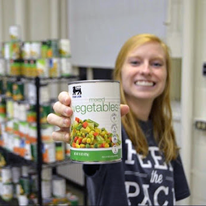Women holding up can of food and smiling at food pantry